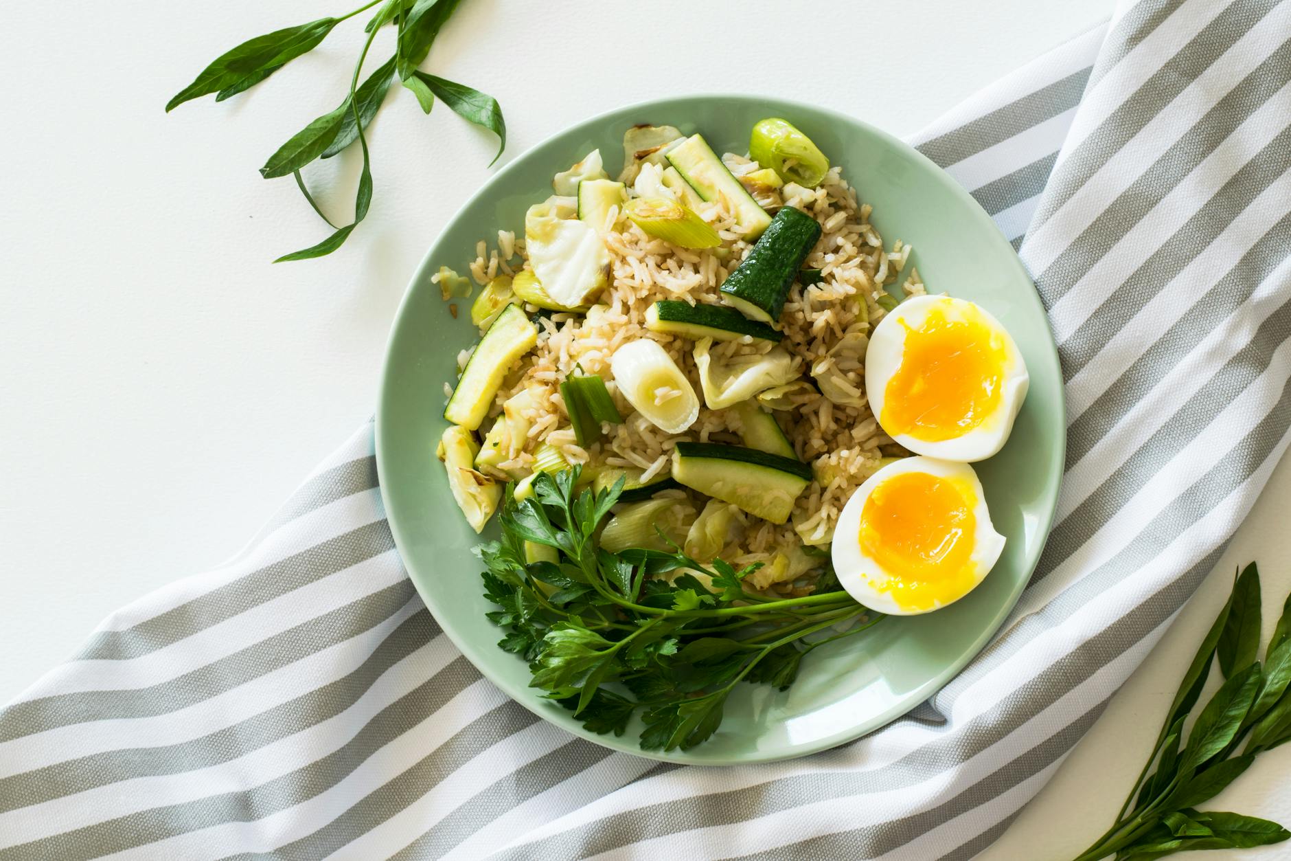 fried rice with poached egg zucchini and celery on round green ceramic plate